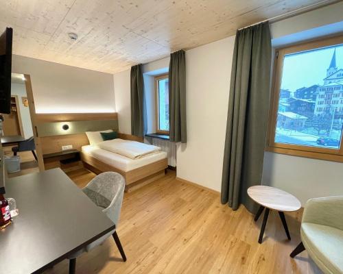 a hotel room with a bed and a table at Boutique und Bier Hotel des alpes in Fiesch