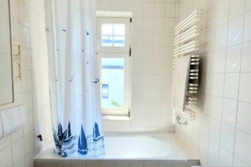 uma casa de banho branca com um chuveiro e uma janela em Kaethchen em Warnemünde