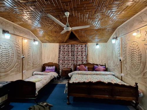 a bedroom with two beds and a ceiling fan at Houseboat Young Snow View Front Line Dal Lake in Srinagar