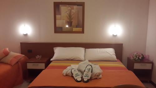 a bedroom with a bed with a pair of shoes on it at Hotel Garden Ristorante in Tabiano