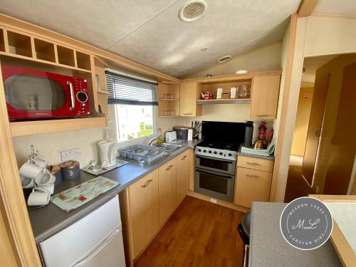 a small kitchen with a stove and a microwave at Happy Days - Beachfields 370 in Chapel Saint Leonards