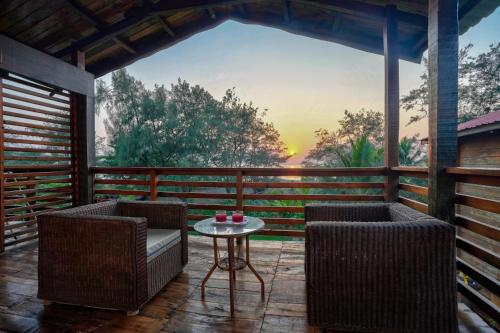 eine Terrasse mit 2 Stühlen und einem Tisch mit Aussicht in der Unterkunft Aqua Marina Beach Cottages in Calangute
