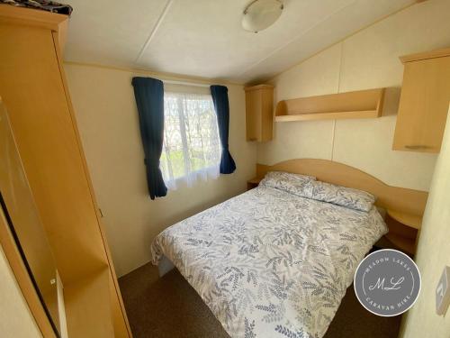 a small bedroom with a bed and a window at Happy Days - Beachfields 370 in Chapel Saint Leonards