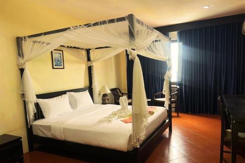 a bedroom with a canopy bed and a table at Harmony Patong Hotel in Patong Beach