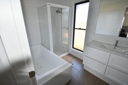 La salle de bains blanche est pourvue d'une baignoire et d'un lavabo. dans l'établissement Ascot Gardens Serviced Apartments, à Dubbo