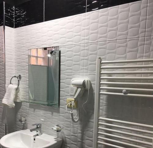 W białej łazience znajduje się umywalka i lustro. w obiekcie Bujtina Vasili w mieście Korcza