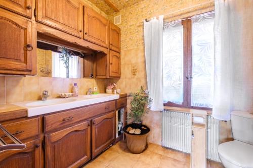 une cuisine avec des armoires en bois, un évier et une fenêtre dans l'établissement Appartement Vallon des prés, à Villeneuve-Loubet