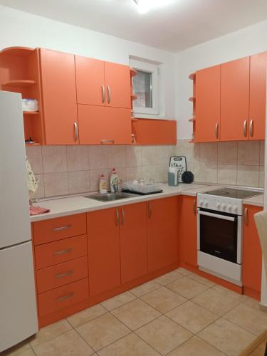 une cuisine orange avec des appareils blancs et des armoires orange dans l'établissement Tea, à Sremska Mitrovica