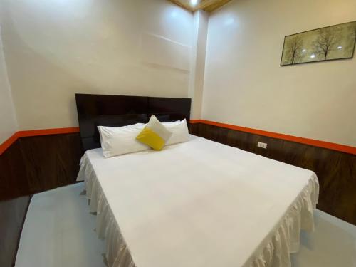 una camera con letto bianco e cuscino giallo di S Apartelle a Zamboanga