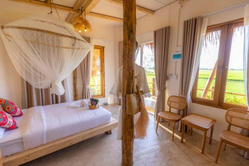 a bedroom with a canopy bed and a window at Nakhao Cottage in Ban Wat Tan