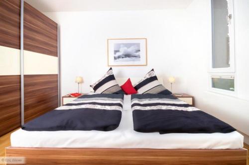 1 dormitorio con 1 cama con almohadas blancas y negras en Residenz/Eric, en Warnemünde