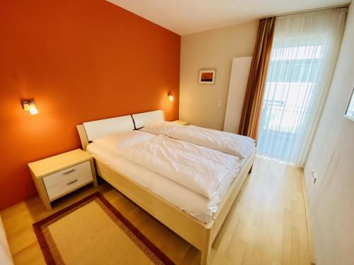 1 dormitorio con cama blanca y pared de color naranja en Residenz/Koralle en Warnemünde