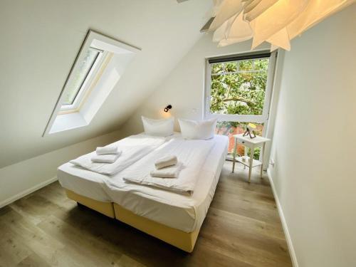 a bedroom with a bed with white sheets and a window at Sommerhaus am Bach in Warnemünde