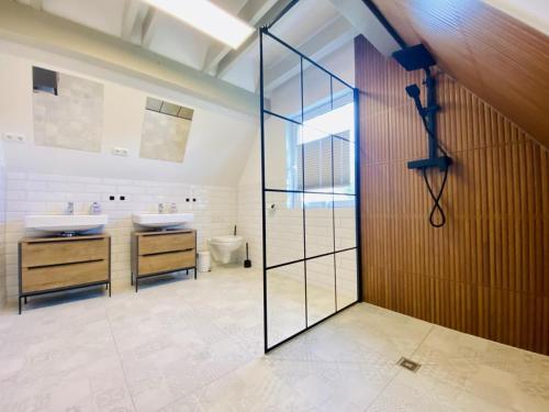 a bathroom with two sinks and a glass shower door at Sommerhaus am Bach in Warnemünde