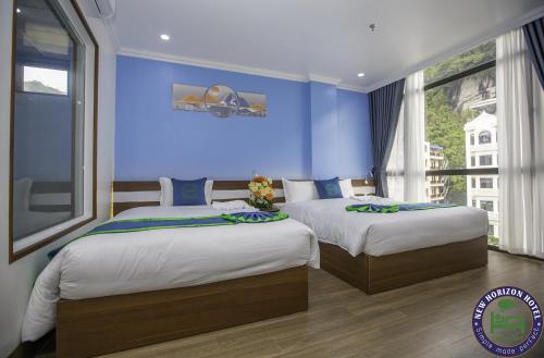 two beds in a bedroom with a blue wall at CHÂN TRỜI MỚI -NEW HORIZON HOTEL in Cat Ba