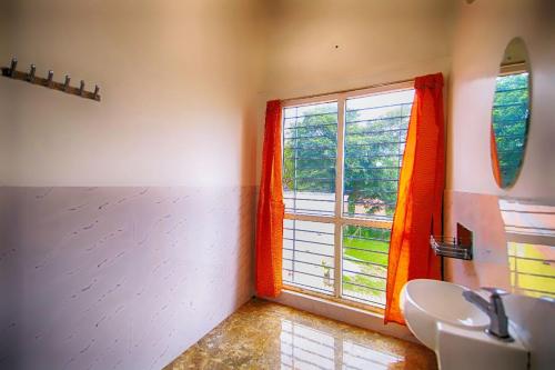 ein Badezimmer mit einem Waschbecken und einem großen Fenster in der Unterkunft Leo Inn in Yercaud