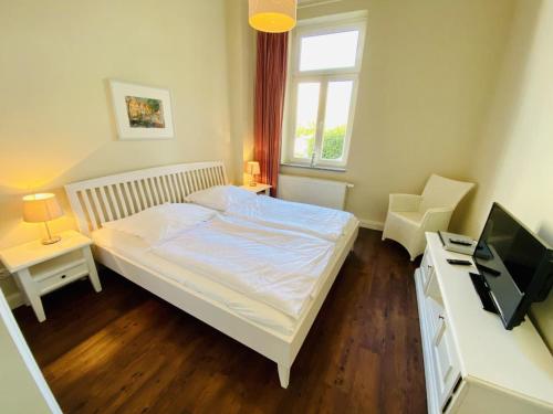 een slaapkamer met een bed en een bureau met een televisie bij Villa Seevogel/Kormoran in Warnemünde