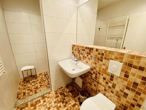 een badkamer met een wastafel, een toilet en een spiegel bij Villa Seevogel/Kormoran in Warnemünde