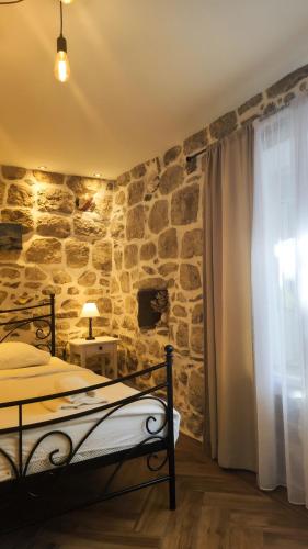a bedroom with a stone wall with a bed and a window at Step to Kotor bay Perast in Perast