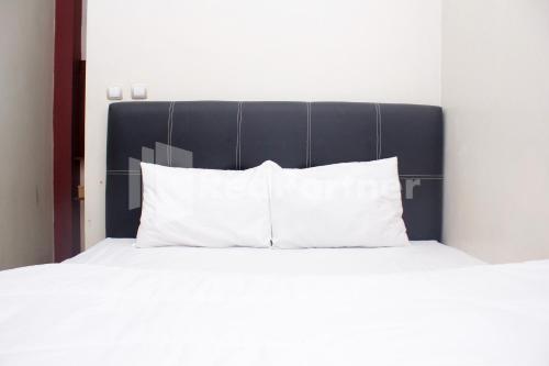 a bed with white pillows and a black headboard at Hotel Baby Angel Dieng Mitra RedDoorz in Garung