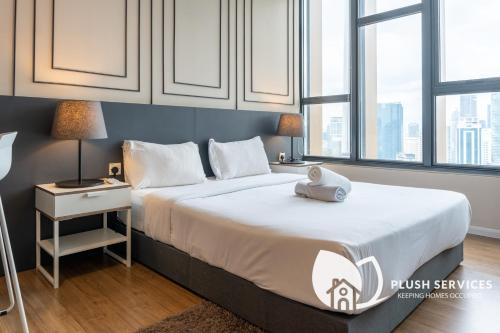 een slaapkamer met een groot bed met witte lakens en ramen bij CeylonZ Suites by Plush in Kuala Lumpur