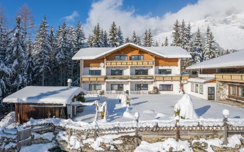 una casa de madera en invierno con nieve en Hotel Ramsaueralm, en Ramsau am Dachstein