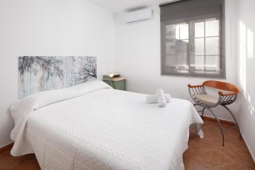 a white bedroom with a white bed and a chair at Apartamento Miramar in Cala del Moral