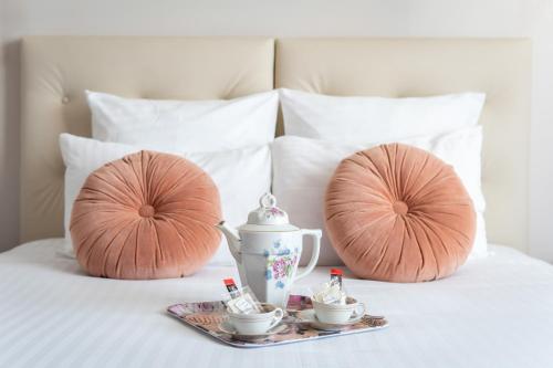 zwei Kissen und ein Tee-Set auf dem Bett in der Unterkunft Hôtel Le Grand Barnum in Francheville