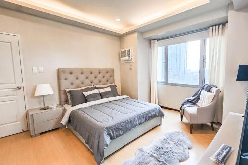 a bedroom with a bed and a chair and a window at Avant Spacious Sanctuary with the best view in BGC in Manila