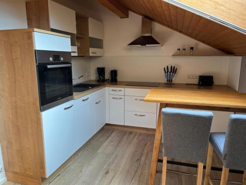 a kitchen with white cabinets and a wooden table at NEU! FeWo Mansi in Chiemgau in Kienberg