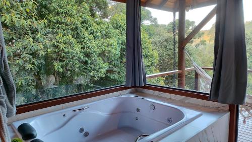 a bath tub in a room with a window at Chalé Valle dos sonhos in Gonçalves