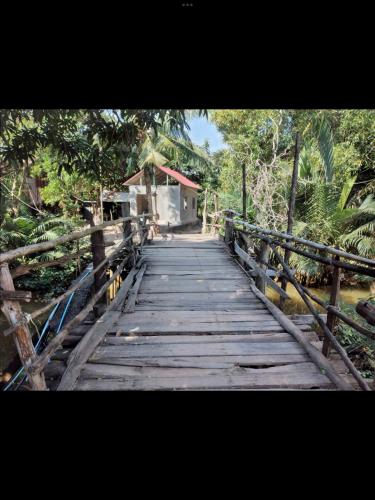 a wooden bridge over a river with a house at Pirates Arms Backpackers in Kampot