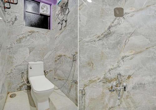 a bathroom with a toilet and a marble wall at Hotel Indiana Palace in Kānpur