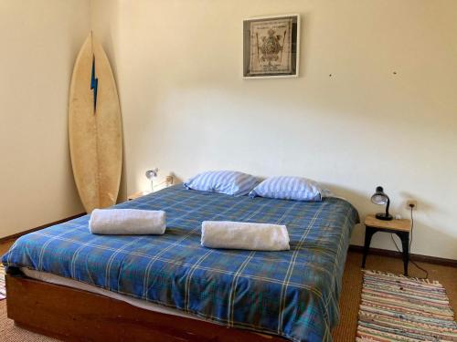 a bedroom with a bed with two pillows and a surfboard at Maceda Surf Camp in Maceda