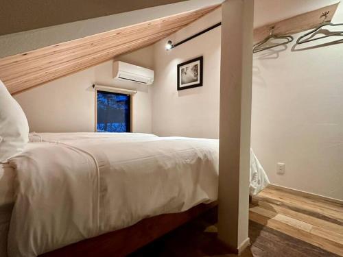 a bedroom with a large white bed and a window at The Misorano Cottage in Hakuba