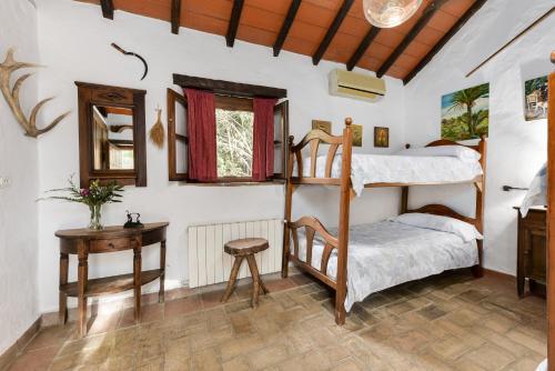 a bedroom with two bunk beds and a table at Cortijo rural las aves in Jimena de la Frontera