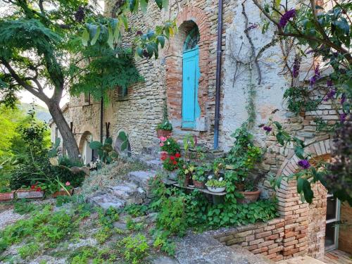 a brick building with a blue window and a bunch of plants at Antico-Borgo-Le-Torricelle-Alle-3 in Piandimeleto