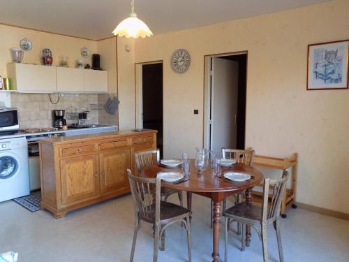 une cuisine avec une table et des chaises ainsi qu'une cuisine avec une cuisinière dans l'établissement Saint Georges de Didonne - APPARTEMENT - résidence PROCHE PLAGE avec ascenseur, à Saint-Georges-de-Didonne