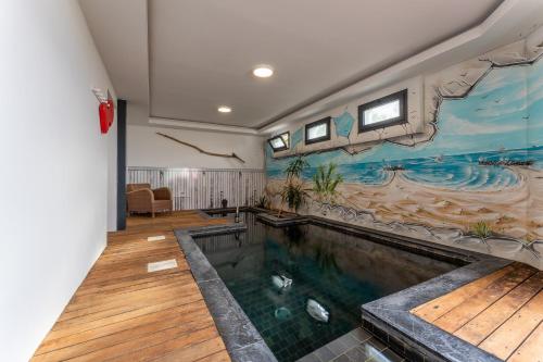 - une piscine dans une pièce ornée d'une peinture murale dans l'établissement Le Littoral - Piscine et plage aux pieds, au Grau-dʼAgde