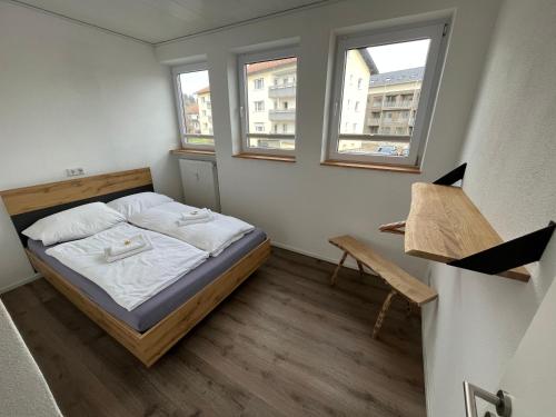 a small bedroom with a bed and two windows at Ferienwohnung im Stadtzentrum in Oberstaufen