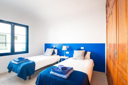 2 camas en una habitación de color azul y blanco en Blancazul Mingo Bajo, en Playa Blanca
