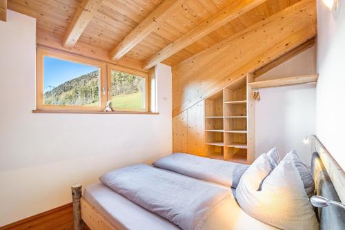 a bed in a tiny house with a window at Kreuzplonhof Apt Karspitz in Luson
