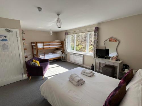 Strathassynt Guest House في غلينكو: غرفة نوم بسرير وكرسي ونافذة