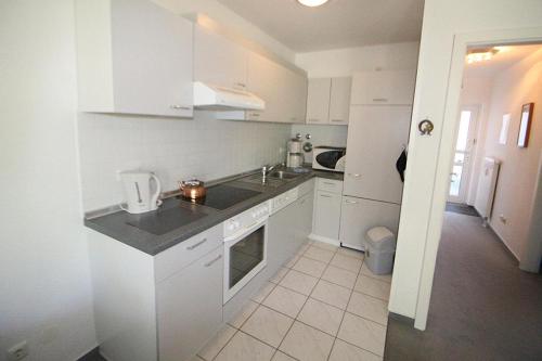a white kitchen with a sink and a stove at Apartmentvermittlung Mehr als Meer - Objekt 30 in Niendorf