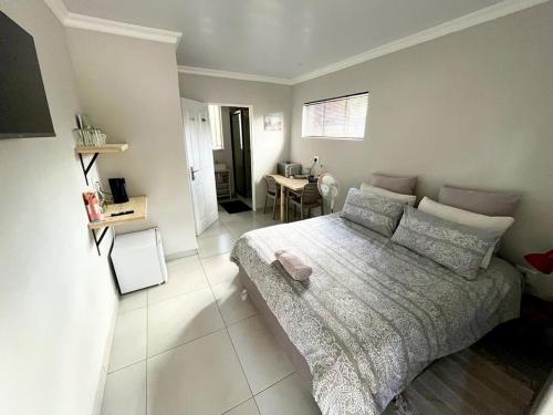 1 dormitorio con cama y escritorio. en Wamelia Guesthouse, en Bloemfontein