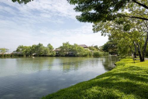 a body of water with trees and grass next to it at Ploen Pirom in Lat Krabang