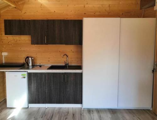 a kitchen with a white refrigerator and wooden cabinets at Domki u Szostaków in Dąbki