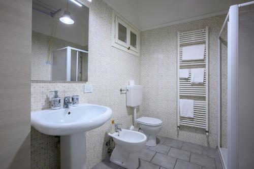 uma casa de banho branca com um lavatório e um WC em La casa del Sole em Piacenza