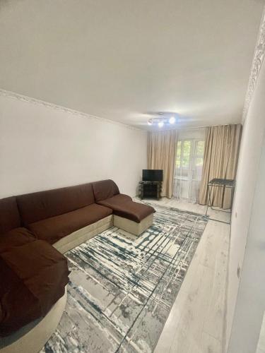 een woonkamer met een bank en een tapijt bij Чудесный квартира in Alma-Ata