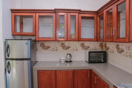 a kitchen with wooden cabinets and a refrigerator at Sun See Villa Hikkaduwa in Hikkaduwa